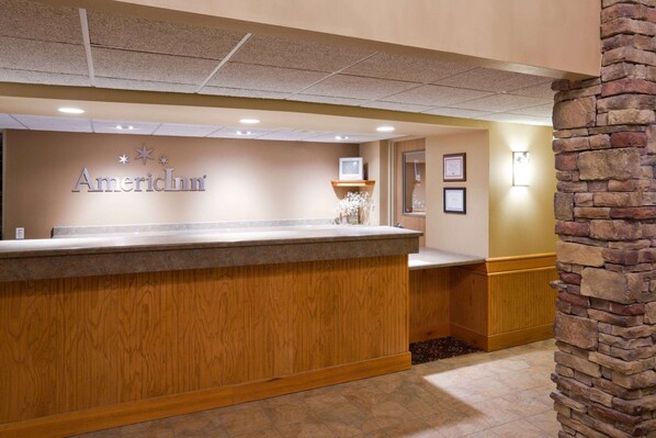 A reception desk with a wooden counter and a sign that reads "AmerInn". - AmericInn by Wyndham Jackson (Jackson)