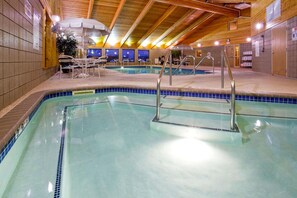 An indoor swimming pool with clear water, surrounded by lounge chairs and umbrellas. - AmericInn by Wyndham Jackson (Jackson)