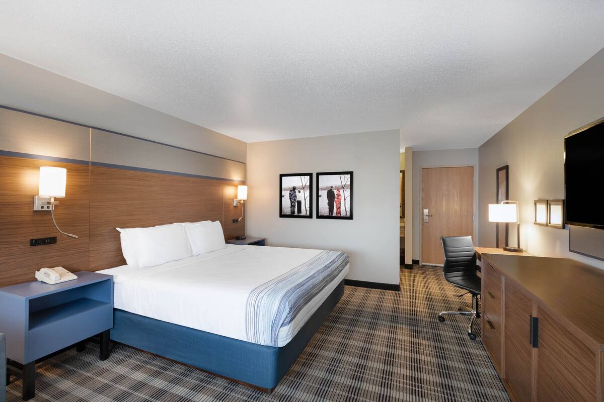 Una habitación de hotel con cama, mesitas de noche, escritorio, silla y televisión.