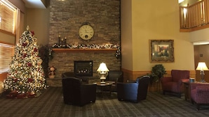 A cozy lobby with a fireplace, a decorated Christmas tree, comfortable seating, and a clock on the wall. - AmericInn by Wyndham Jackson (Jackson)