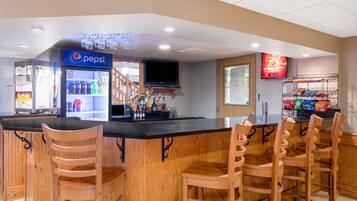 A bar area with a Pepsi refrigerator, a television, and a snack display.