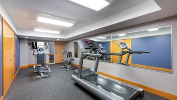 A gym with treadmills, weight machines, and a mirrored wall.