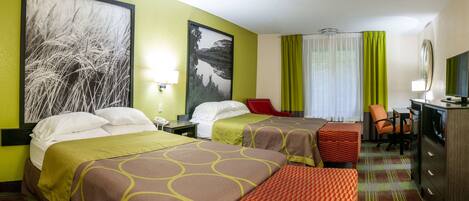 A hotel room with two beds, a desk, a chair, a TV, and artwork on the walls.
