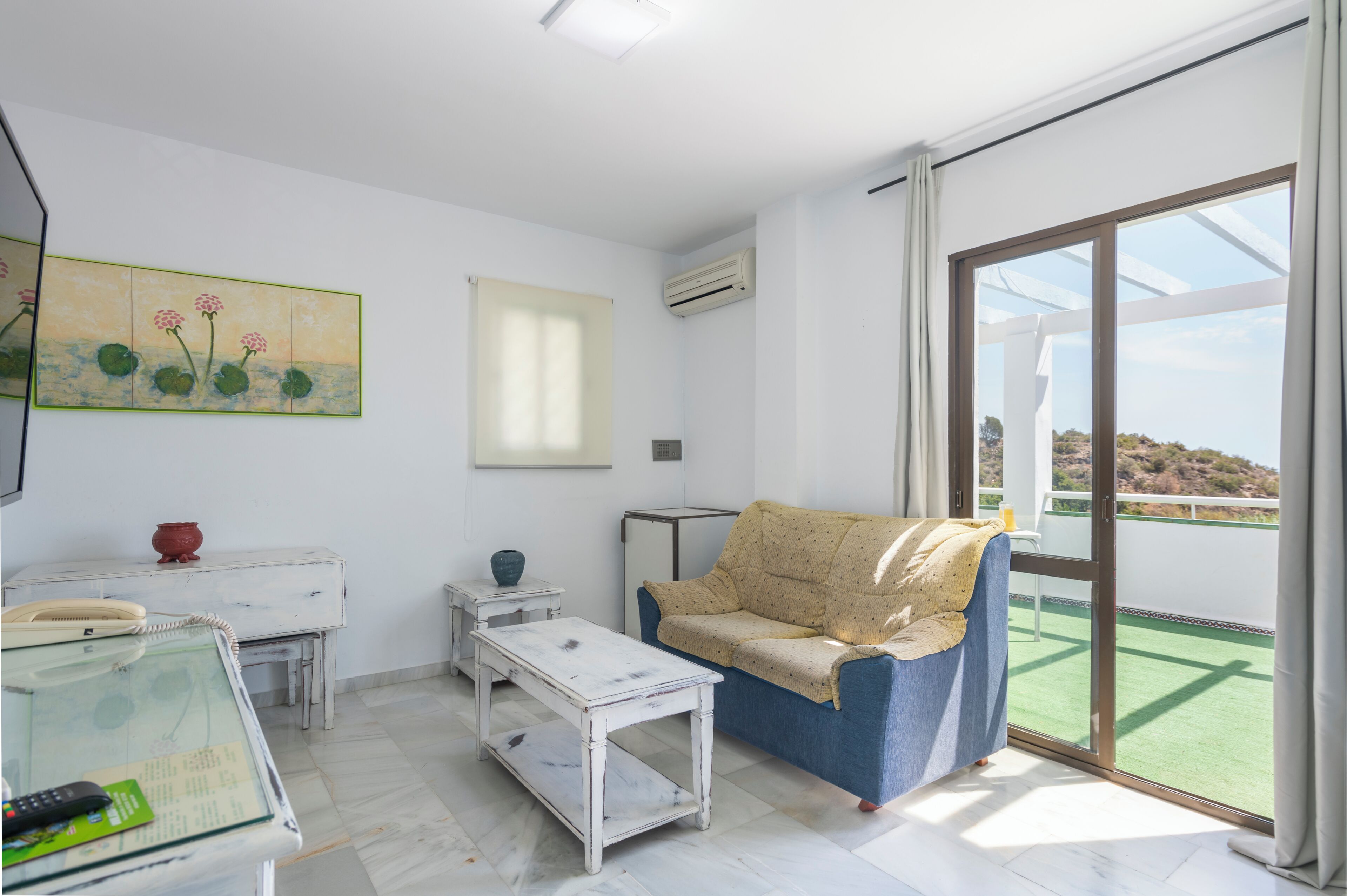 Un soggiorno moderno con un divano, un tavolino, un piccolo tavolo con un vaso e un quadro appeso al muro.