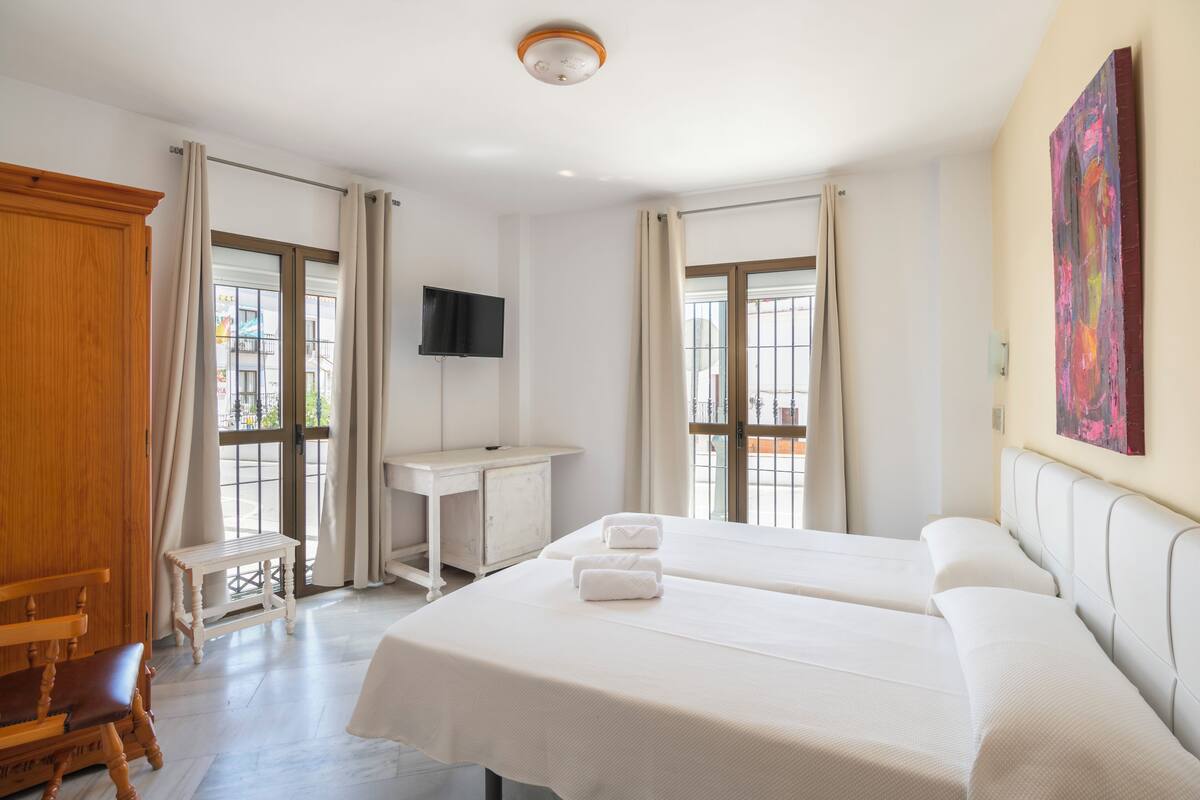 Une chambre d’hôtel avec deux lits, un bureau, une télévision et de grandes fenêtres.