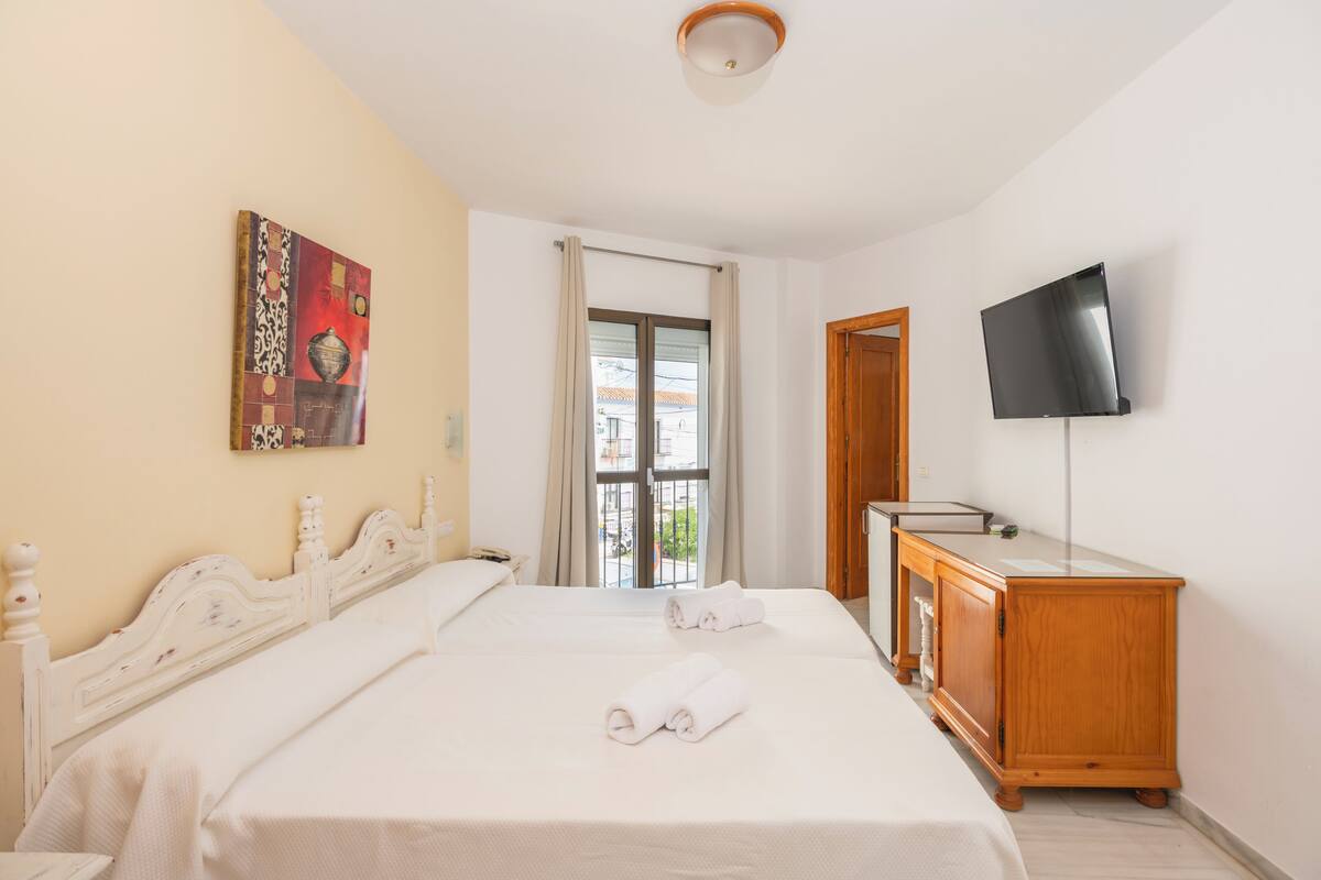 Une chambre d’hôtel avec deux lits, une télévision et une armoire en bois.