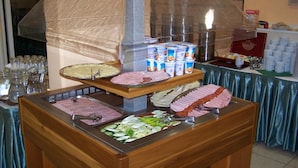 Un buffet proposant une variété de plats, notamment des viandes, des fromages et des légumes frais.