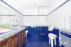 Un baño moderno con ducha de vidrio, lavamanos blanco y piso de azulejos.