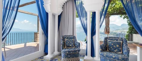 Ein Zimmer mit Meerblick, ausgestattet mit zwei blauen Sesseln und einem gemusterten Boden.