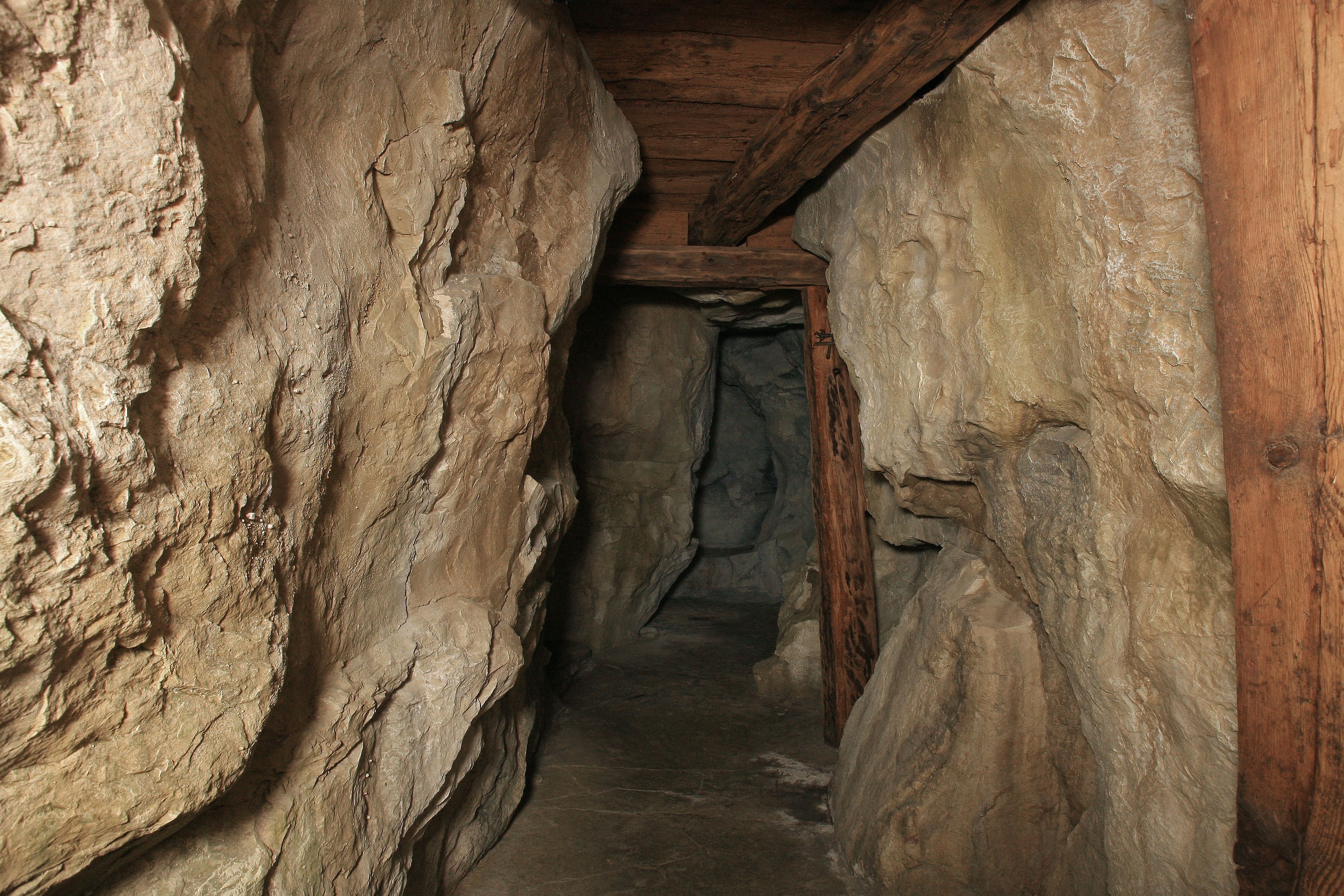 Un estrecho pasaje con paredes de piedra y vigas de madera en el techo.