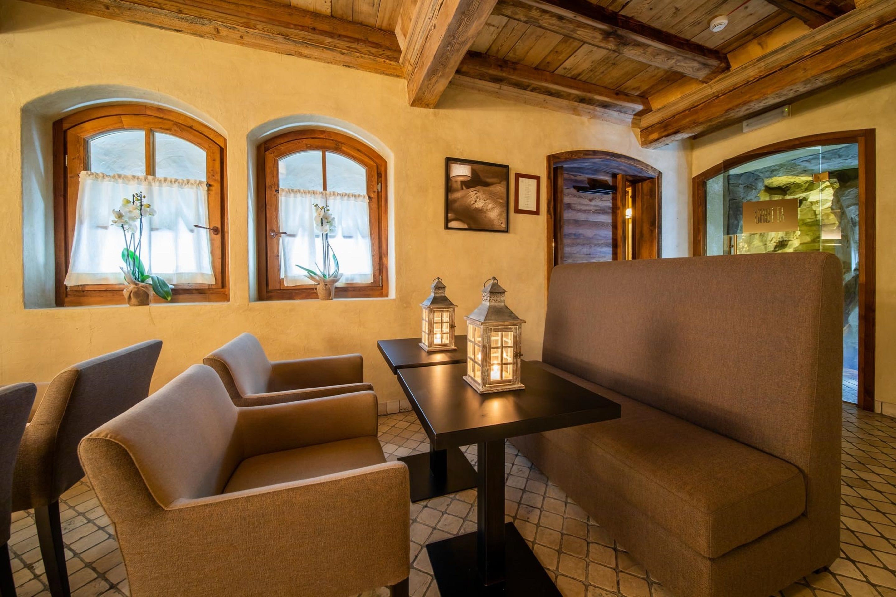 A cozy interior with a sofa, chairs, a table, and two windows with curtains.