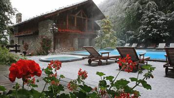 Eine Holzhütte mit Pool und Liegestühlen.
