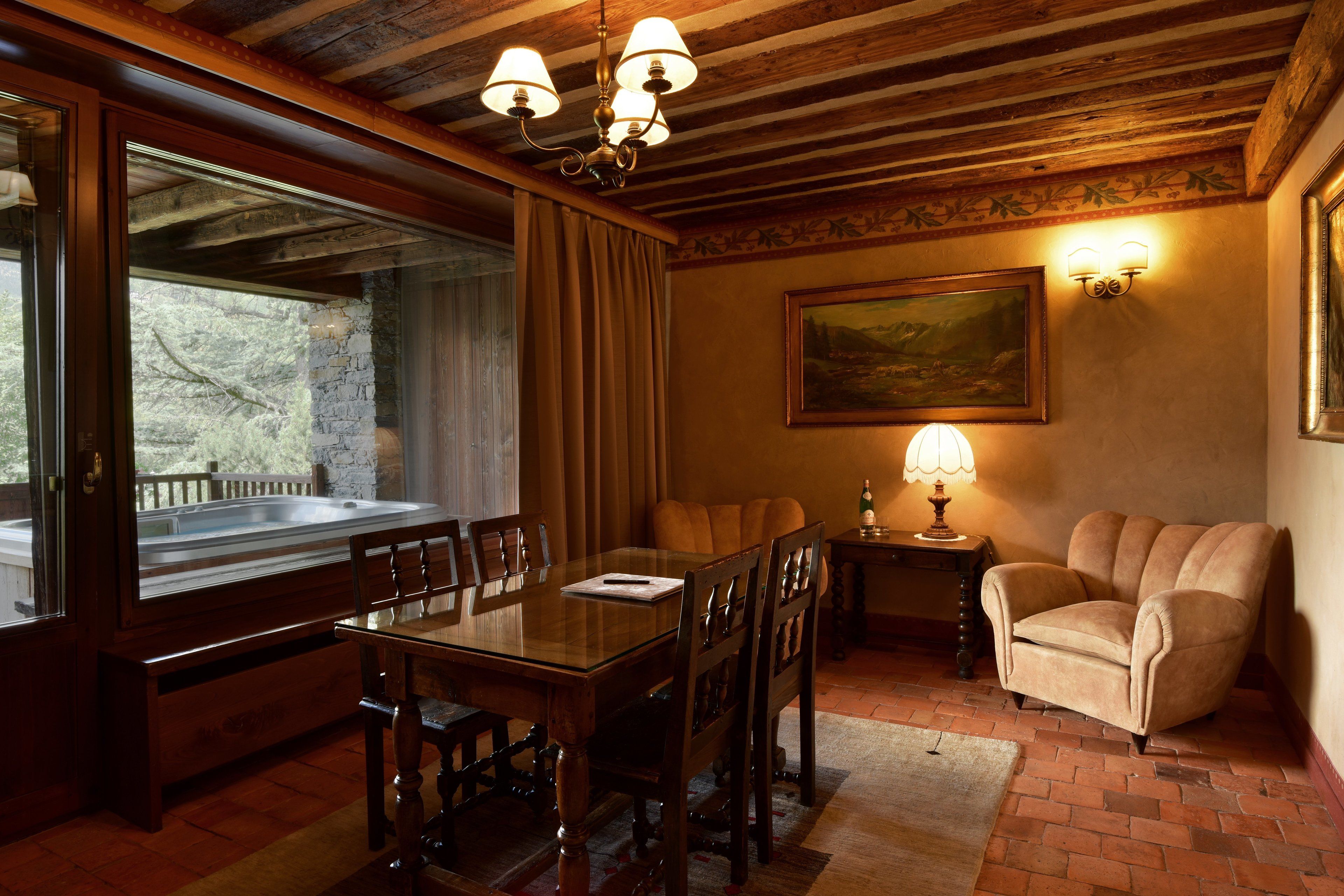 Un coin repas avec une table en bois, des chaises, un lustre, un tableau et une fenêtre avec des rideaux.