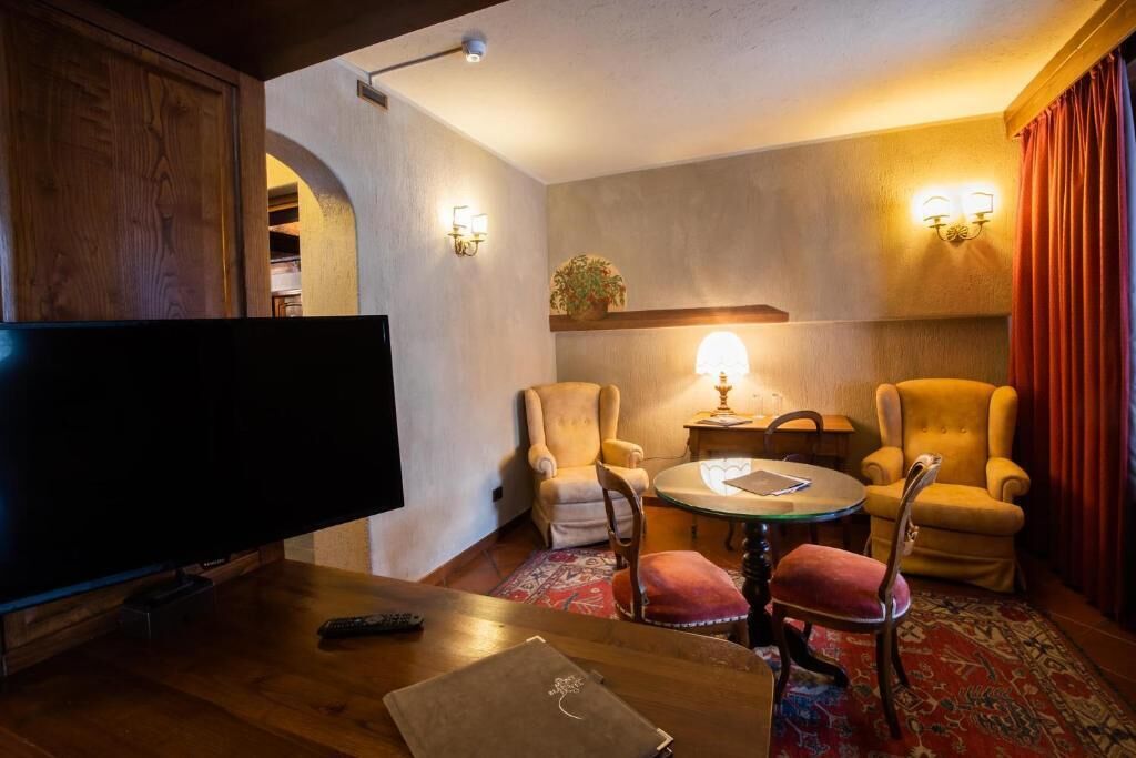 Un salón acogedor con un televisor de pantalla plana, dos sillones, una mesita redonda y una lámpara.