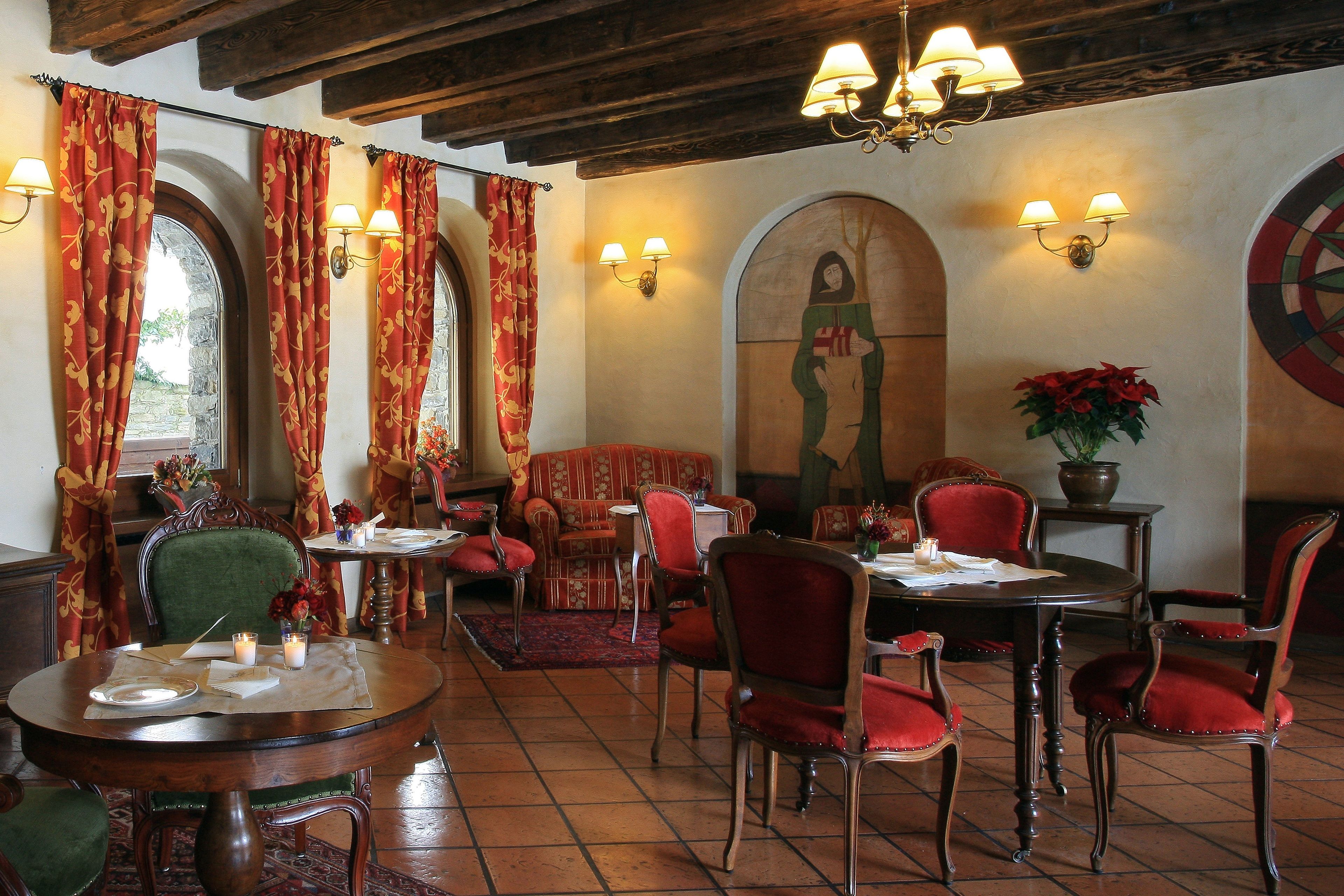 A dining area with red upholstered chairs, a round wooden table, and a chandelier.