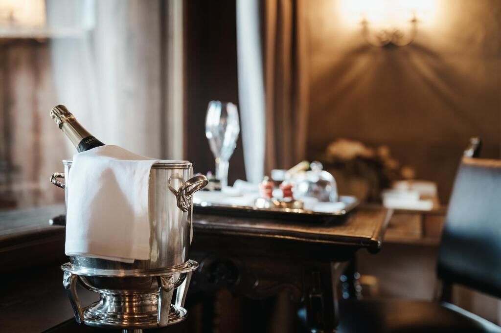 A silver champagne bucket on a table with a bottle of champagne, a glass, and a tray with condiments.