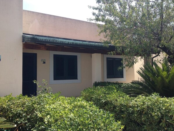 A building with a beige facade, two windows with shutters, and a green roof. - Hotel Aura (Lipari)