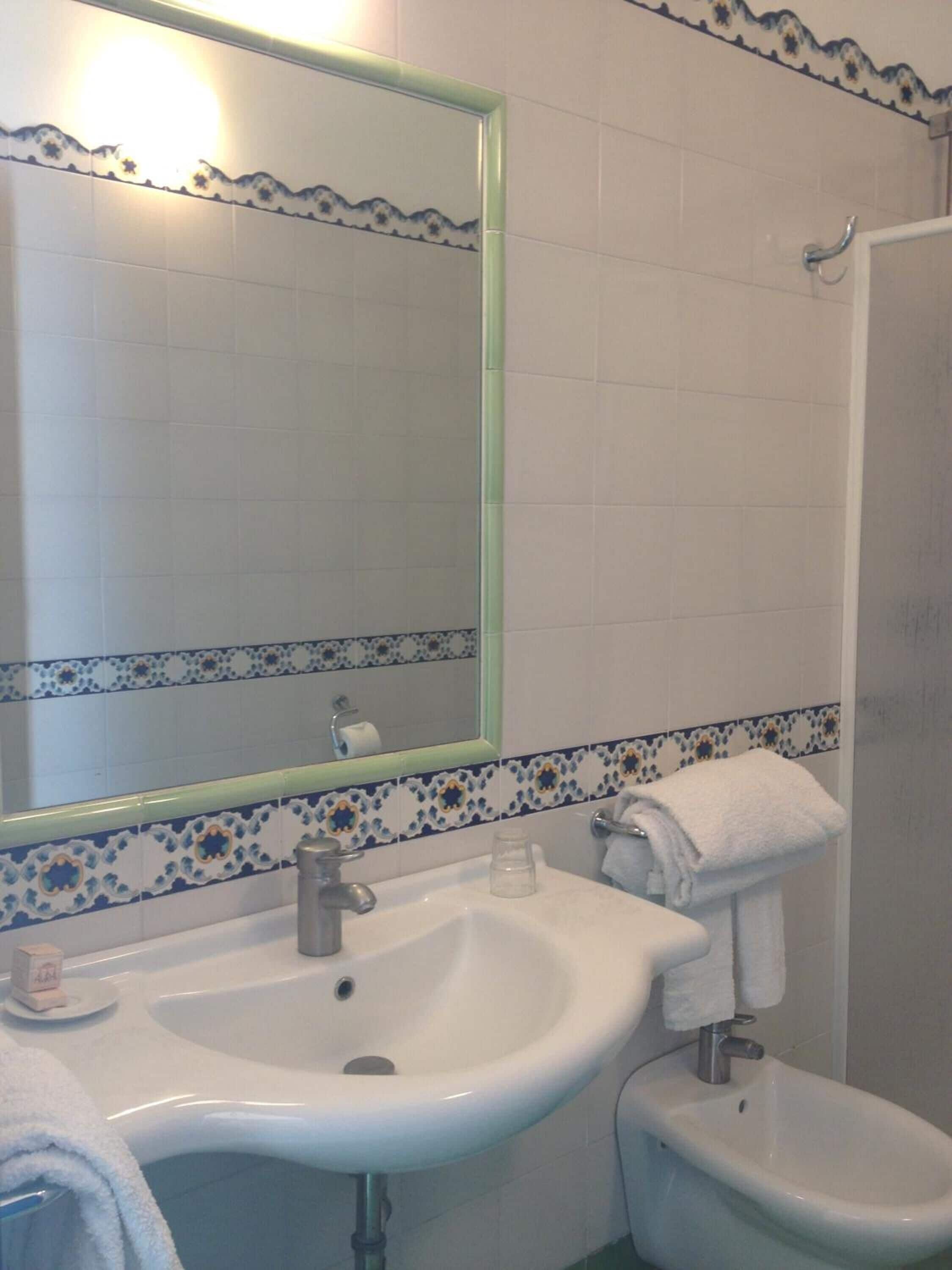 Un baño con lavamanos blanco, un bidé, un espejo y una ducha.