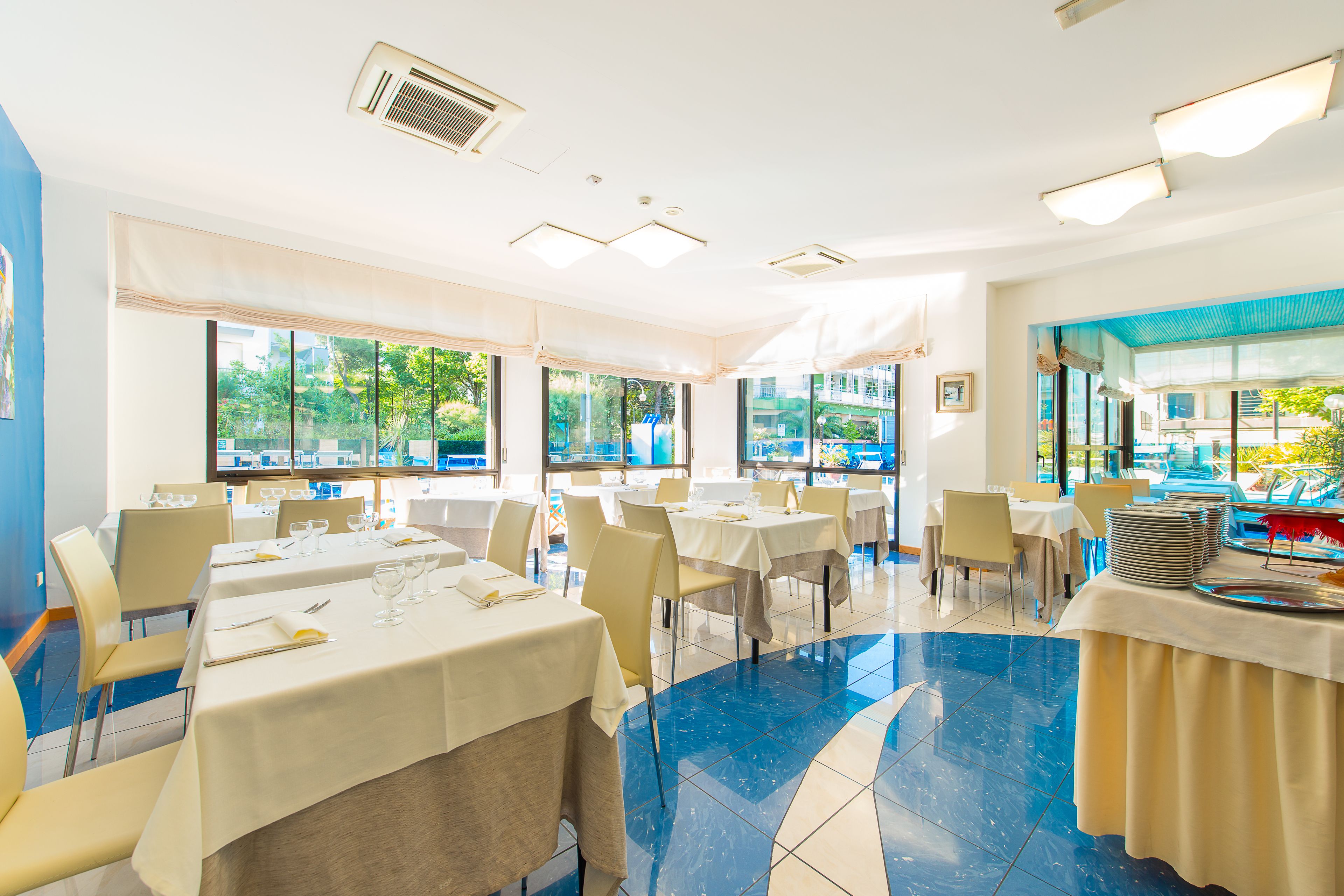 Un restaurante con varias mesas, sillas y un suelo de baldosas azules.