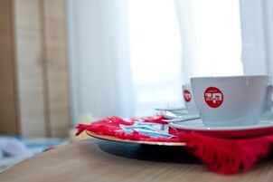 A table with a white cup and saucer, a red napkin, and a placemat.