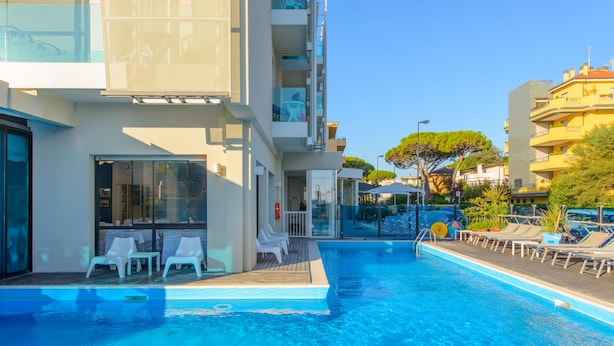 Um hotel moderno com piscina, espreguiçadeiras e vista para a cidade.