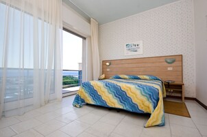 Un dormitorio con cama, mesita de noche, ventana con cortinas e iluminación instalada en la pared.