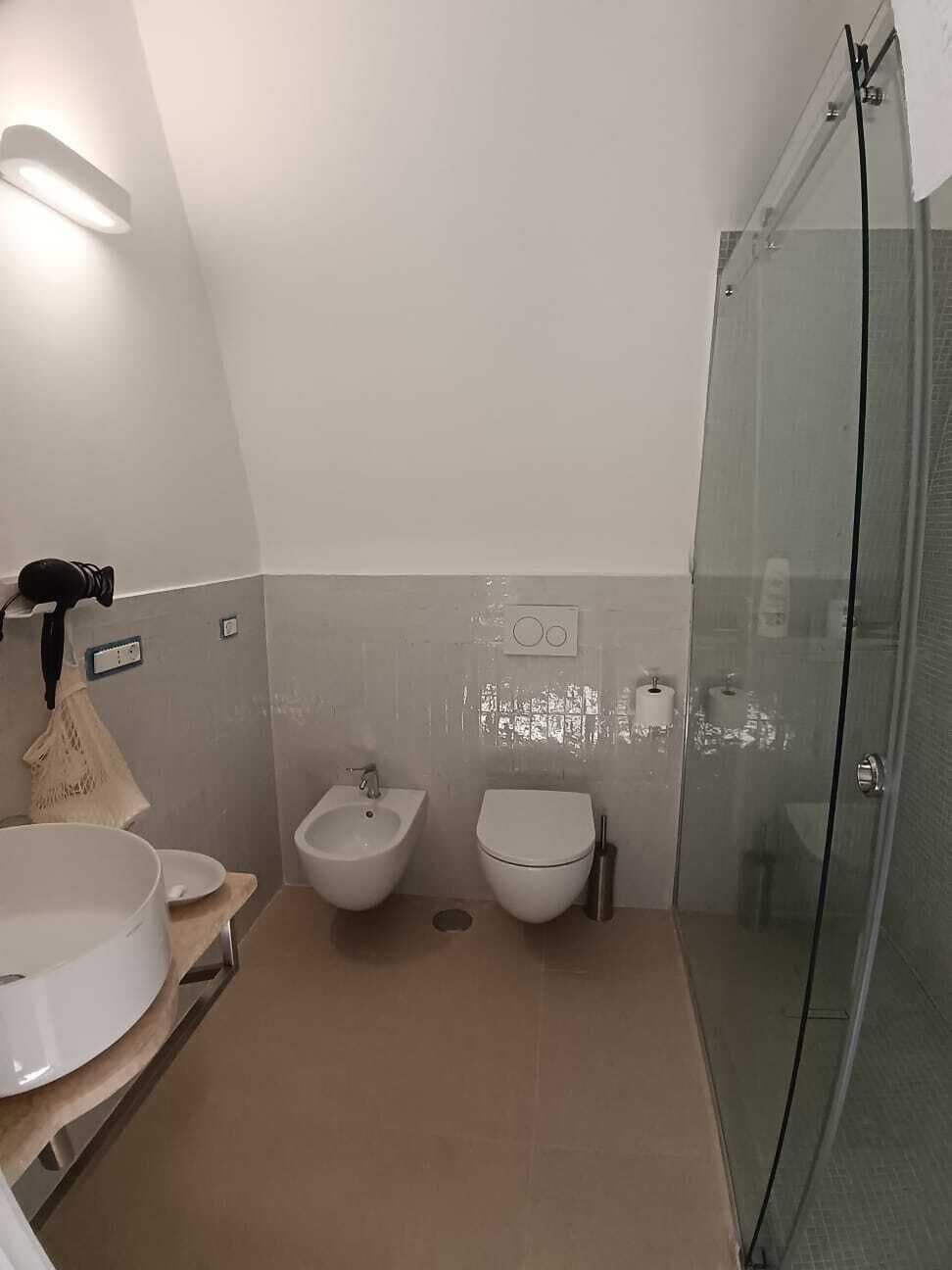 A modern bathroom with a glass shower enclosure, a bidet, and a toilet.
