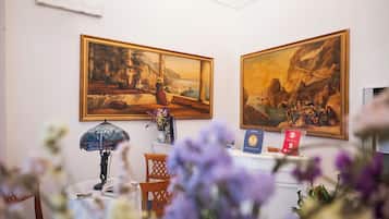 Ein Zimmer mit zwei großen Landschaftsbildern an der Wand, einem kleinen Tisch mit einer Lampe und einem Stuhl.