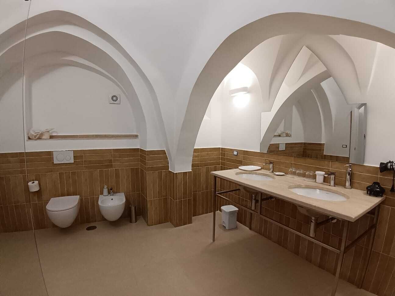 A bathroom with two sinks, a toilet, and a mirror.