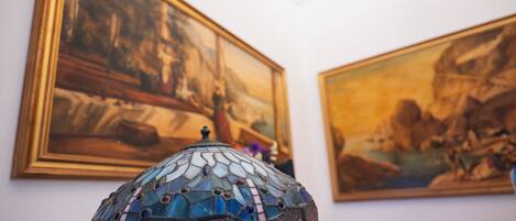 Una habitación con una lámpara de mosaico en primer plano y dos cuadros en la pared.