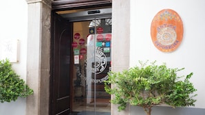 A hotel entrance with a dark wooden door, a Michelin-branded sign, and a small potted plant on the right. - Hotel Antica Repubblica (Amalfi)