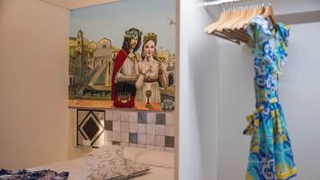 Un dormitorio con un mural de una pareja, una cama con un cojín estampado y un perchero.