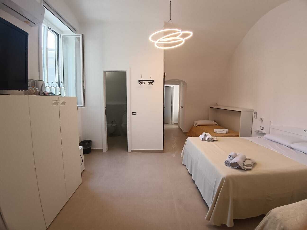 Een hotelkamer met een bed, een kledingkast, een badkamer en een gang.