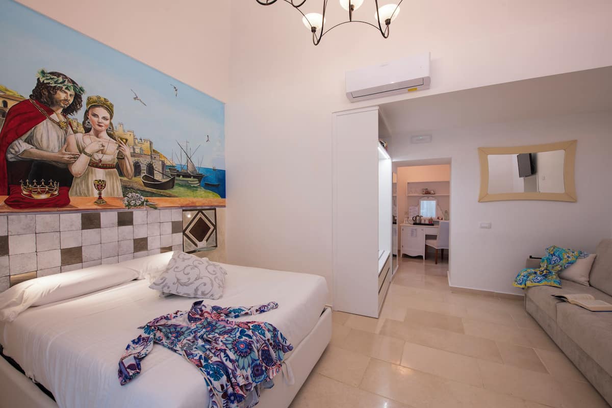 A hotel room with a bed, a painting, a desk, and a chair.
