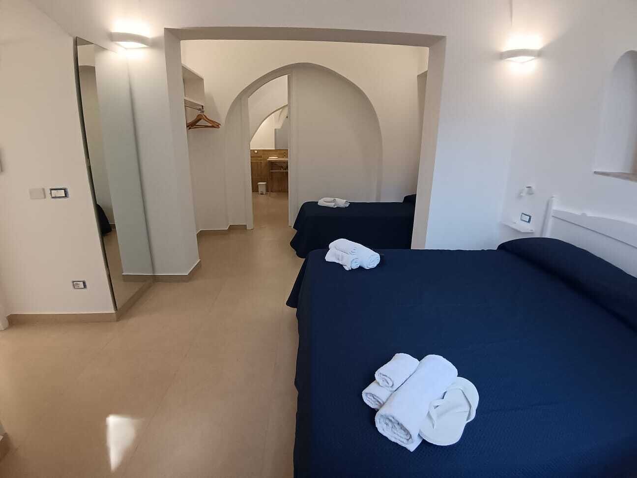 A hotel room with two beds, a walk-in closet, and a hallway leading to a bathroom.