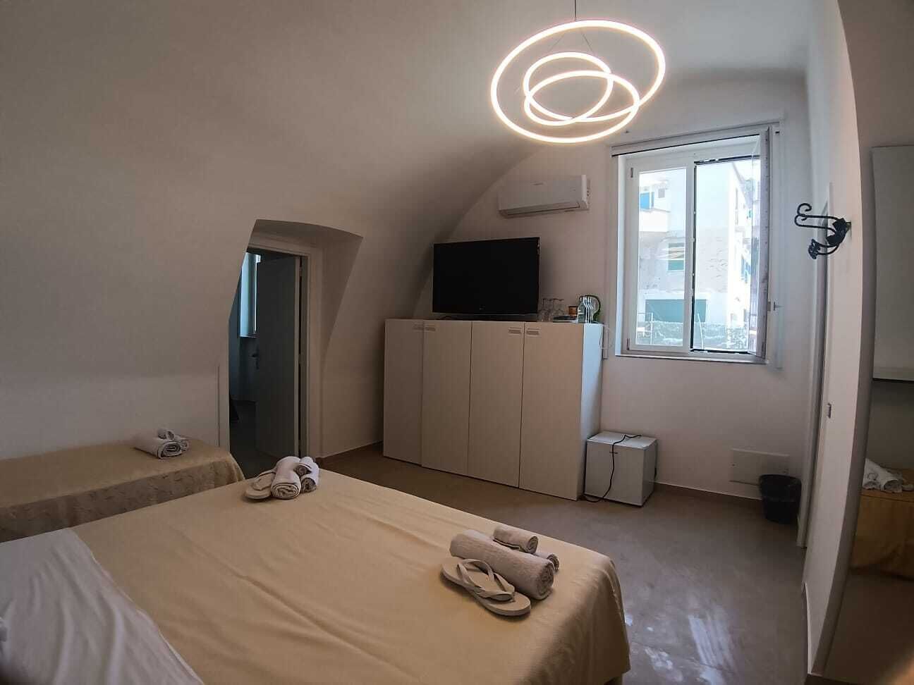 A bedroom with a bed, a wardrobe, a television, and a window.