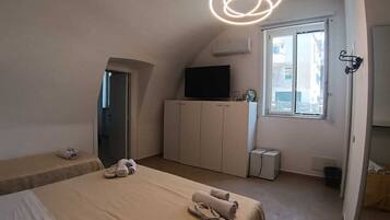 A bedroom with a bed, a wardrobe, a television, and a window.