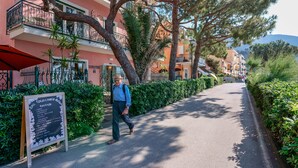 Un hombre camina por un sendero pavimentado junto a un edificio con un cartel que muestra el menú de un restaurante.