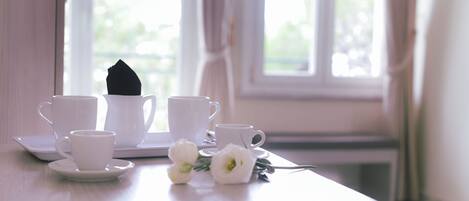 Une table avec des tasses et des soucoupes blanches, une serviette noire et des fleurs blanches.