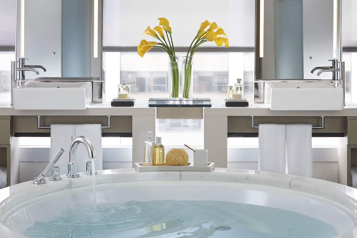 Een aparte badkuip en douche, een diep bad, een regendouche
