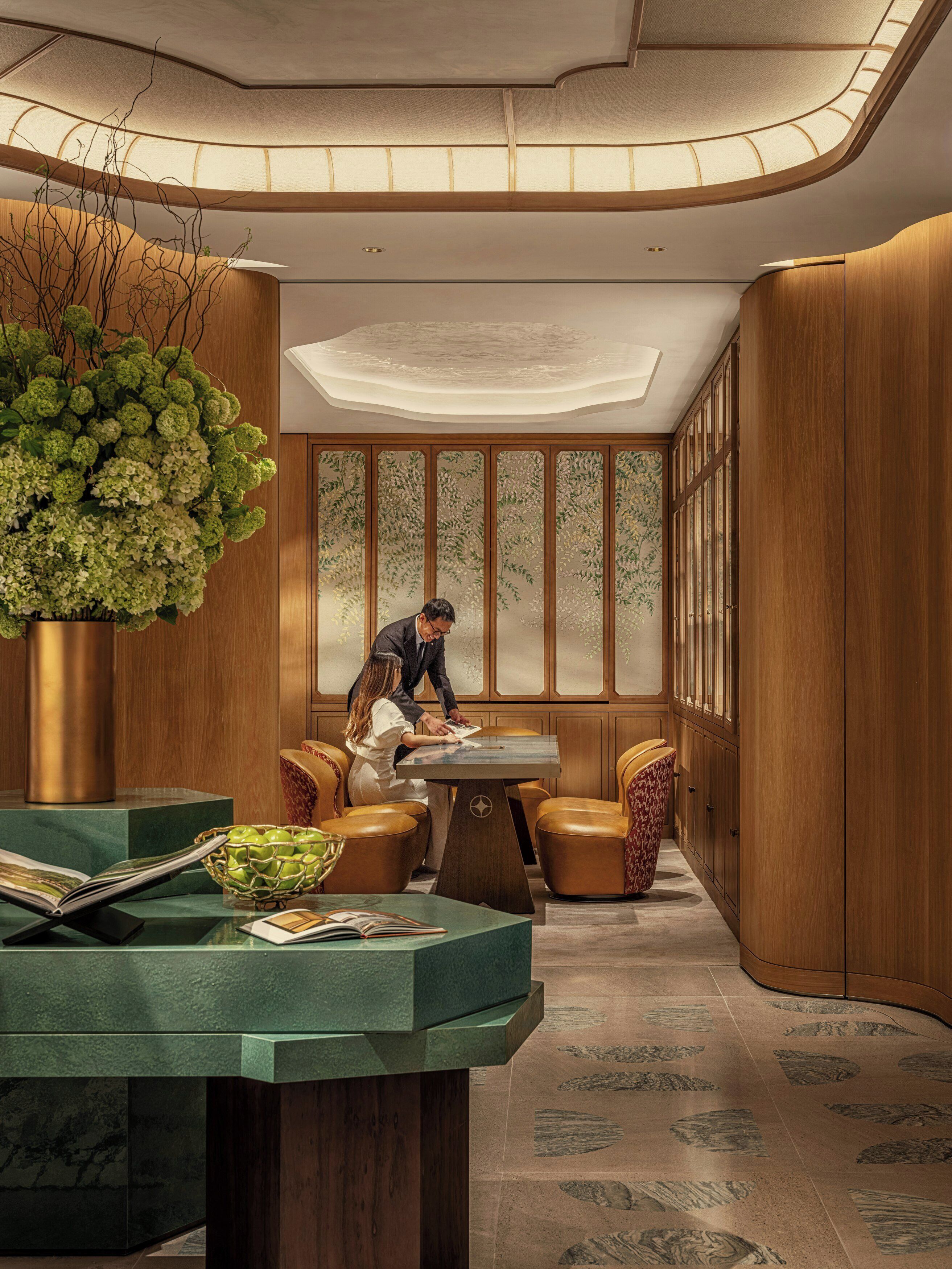 Un interior moderno con un panel de madera, una planta verde grande, una mesa de comedor y sillas de cuero.