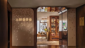 Eine Hotelhalle mit einem auffälligen 'AMBER'-Schild, einem Barbereich mit Flaschen und einer Sitzgruppe.