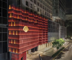 Une façade de bâtiment moderne, caractérisée par un motif de panneaux rouges distinctif et un logo bien visible.
