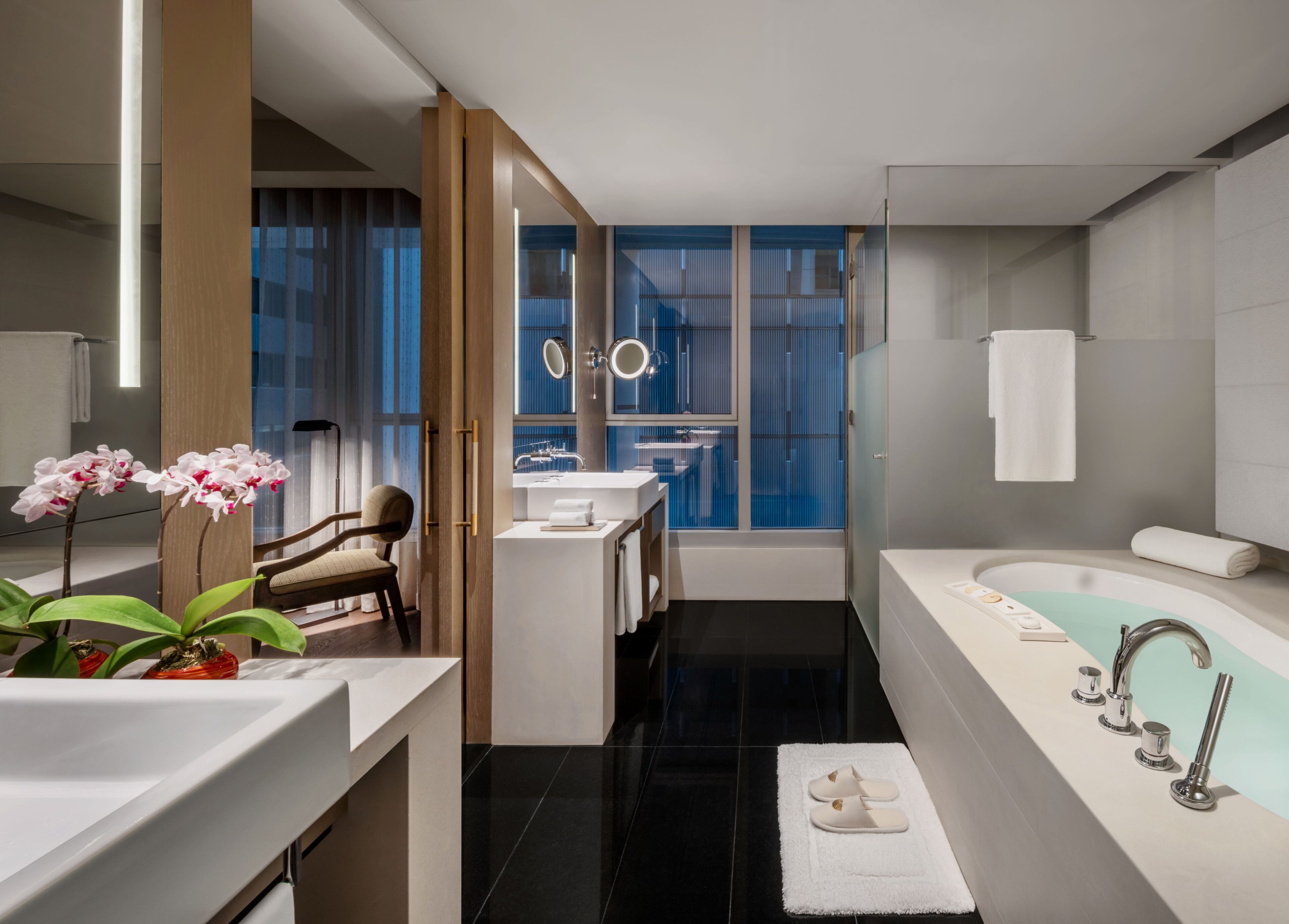 Un baño moderno con bañera, un espejo grande y un lavabo.