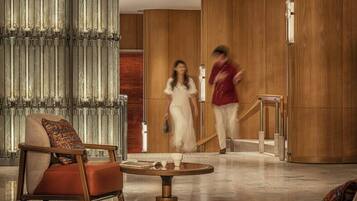 A modern lobby with a seating area, a staircase, and a large window.