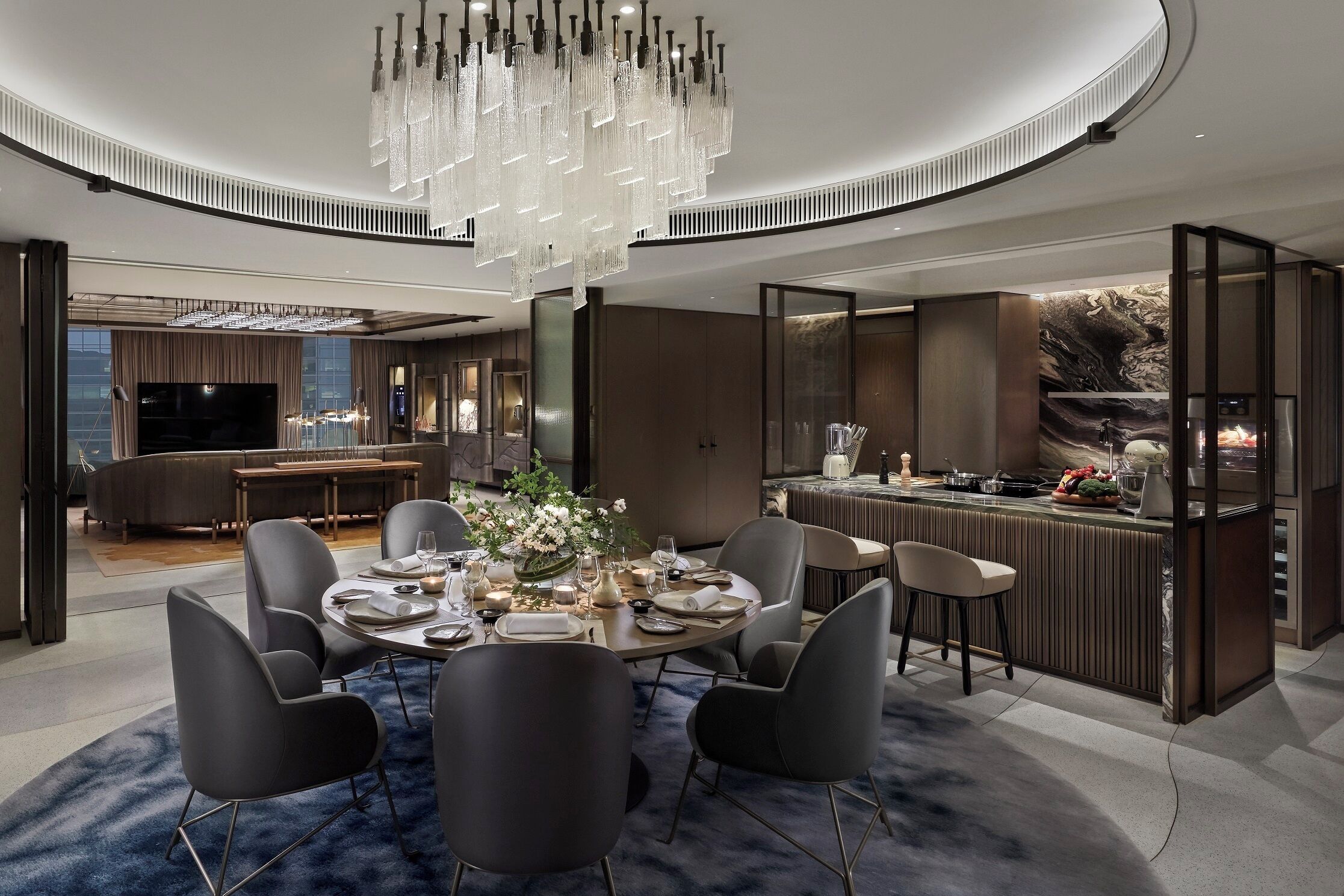 A modern dining area with a round table, chairs, and a chandelier.