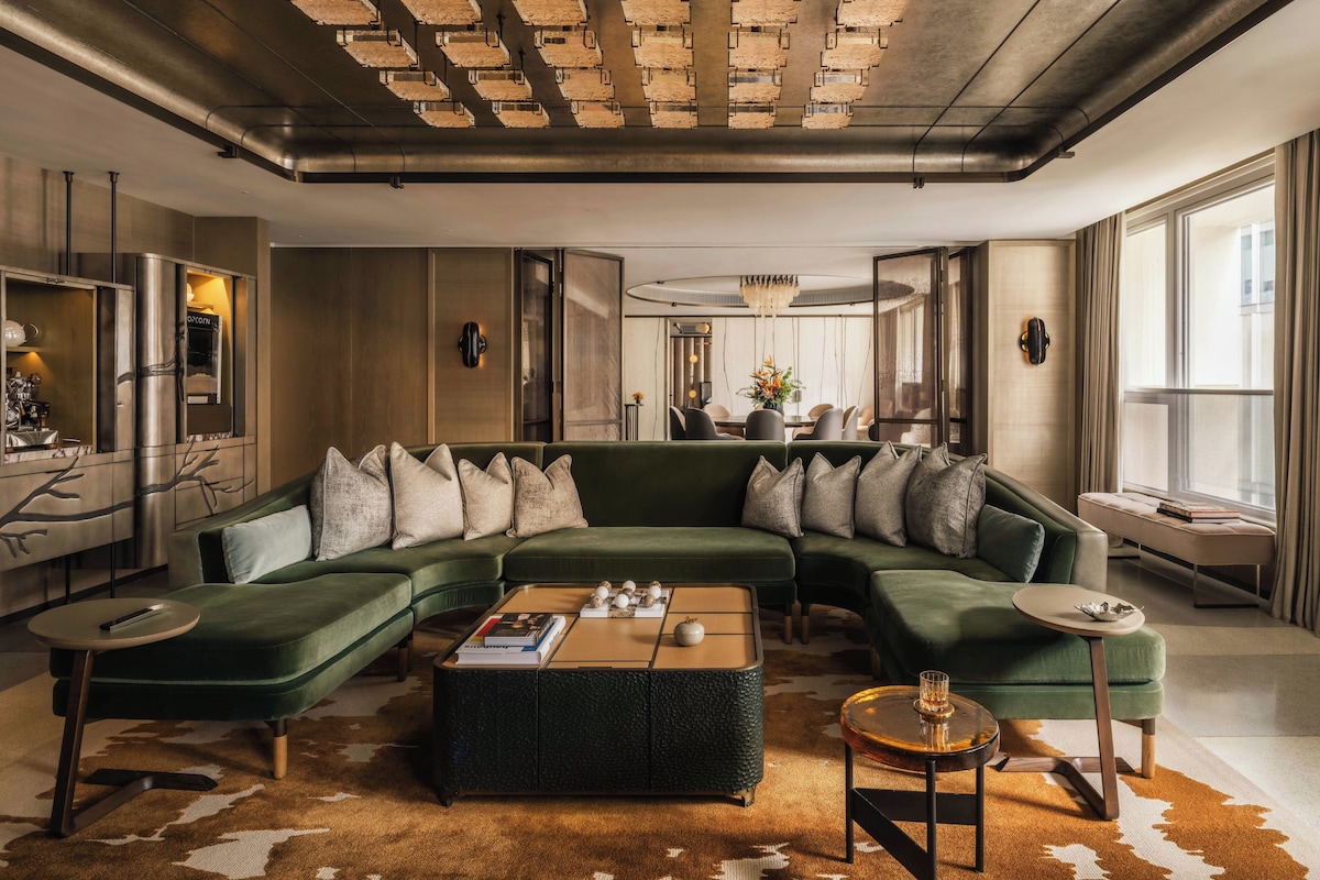 Un salon moderne avec un canapé d’angle, une table basse et un coin repas à l’arrière-plan.