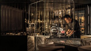 Eine Bar mit einer Marmorplatte, einer Kaffeemaschine und einer Person, die hinter der Theke arbeitet.