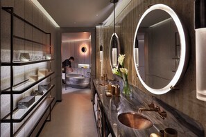 Un baño moderno con un espejo grande, un lavabo de mármol y estantes con artículos de aseo.