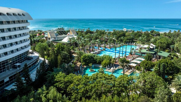 A resort with a large pool, palm trees, and a view of the ocean. - Concorde De Luxe Resort Lara Antalya - Prive Ultra All Inclusive (Antalya)